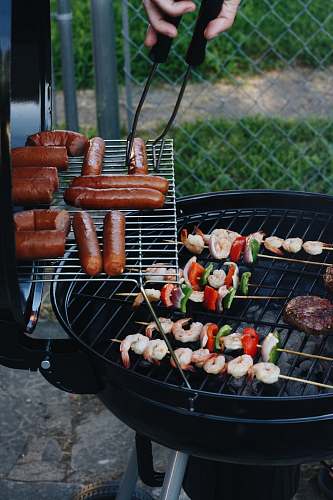 hot dog grilled sausage and meat beside gray chain-link fence bbq